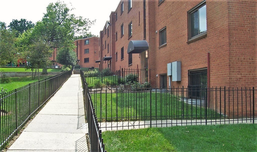 A long brick building with a black fence in front of it.